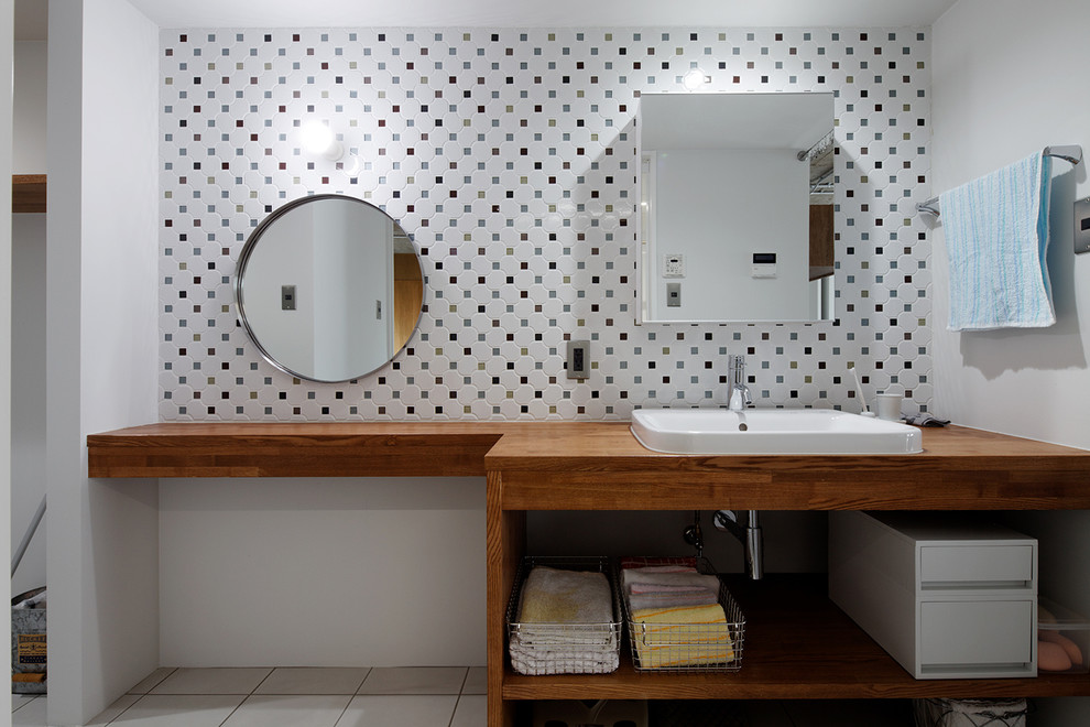 他の地域にあるコンテンポラリースタイルのおしゃれな浴室 (オープンシェルフ、中間色木目調キャビネット、白いタイル、白い壁、オーバーカウンターシンク、木製洗面台、ブラウンの洗面カウンター) の写真