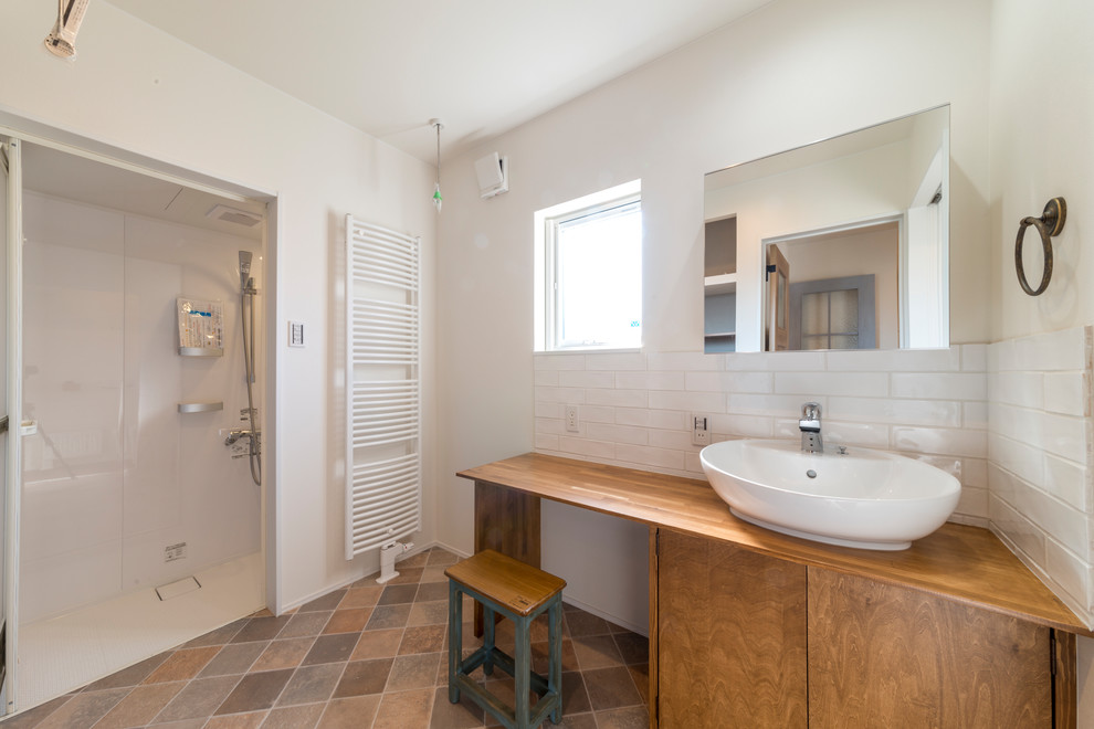 他の地域にあるコンテンポラリースタイルのおしゃれなバスルーム (浴槽なし) (中間色木目調キャビネット、白い壁、ベッセル式洗面器、木製洗面台、茶色い床、フラットパネル扉のキャビネット、アルコーブ型シャワー、白いタイル、開き戸のシャワー) の写真