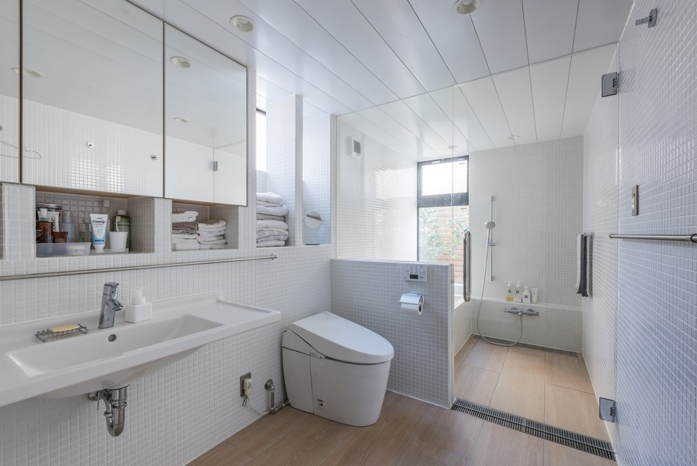 東京都下にあるコンテンポラリースタイルのおしゃれなマスターバスルーム (一体型トイレ	、白いタイル、モザイクタイル、オープンシェルフ、白いキャビネット、アルコーブ型浴槽、シャワー付き浴槽	、白い壁、コンソール型シンク) の写真