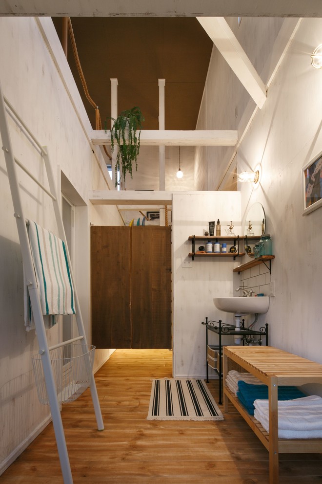 Inspiration för maritima badrum, med öppna hyllor, skåp i mellenmörkt trä, ett väggmonterat handfat, vita väggar och mellanmörkt trägolv