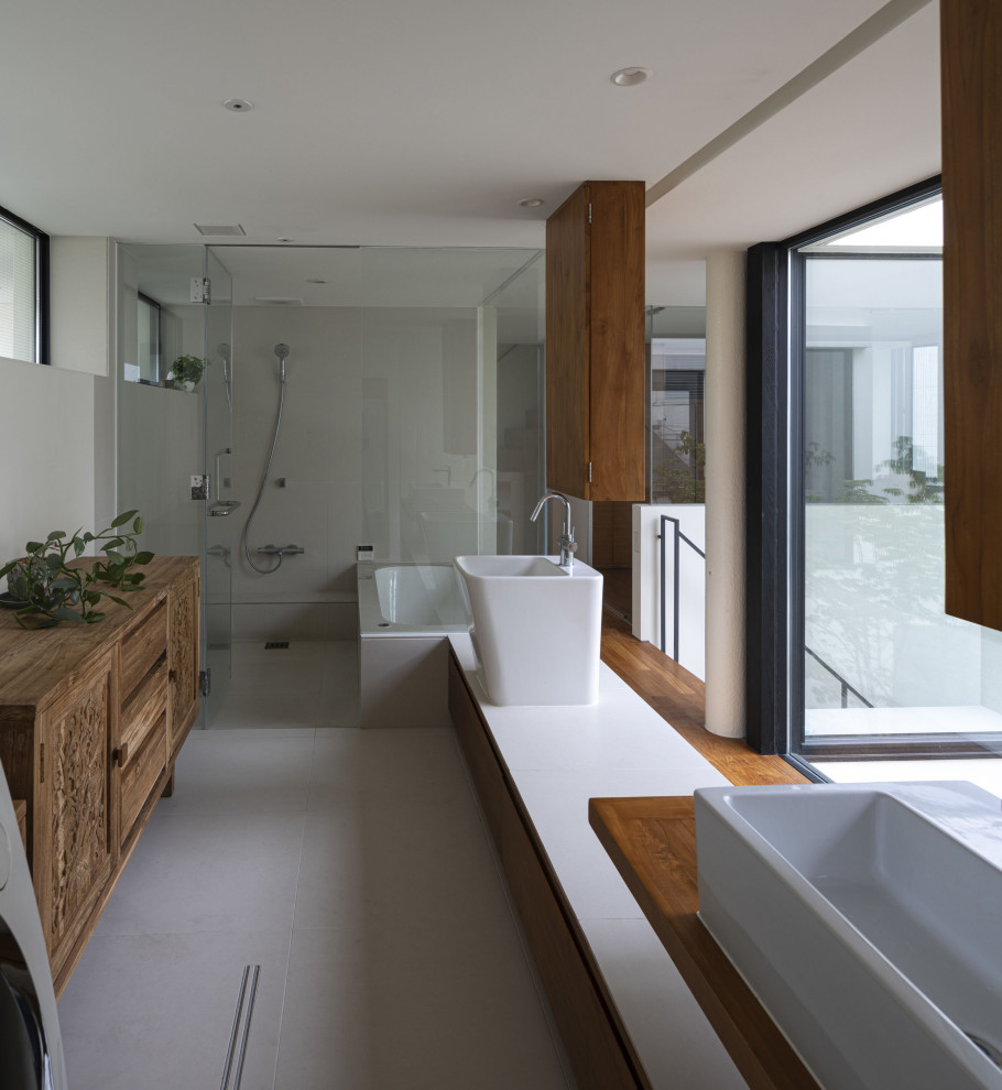 Modern inredning av ett stort vit vitt en-suite badrum, med släta luckor, skåp i mellenmörkt trä, ett platsbyggt badkar, en dusch/badkar-kombination, grå kakel, vita väggar, klinkergolv i porslin, ett fristående handfat, grått golv och med dusch som är öppen