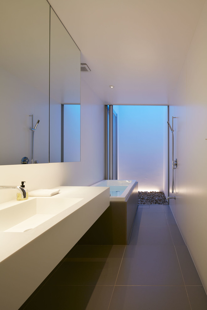 Пример оригинального дизайна: главная ванная комната в стиле модернизм с накладной ванной, душевой комнатой, серой плиткой, белыми стенами, монолитной раковиной и серым полом