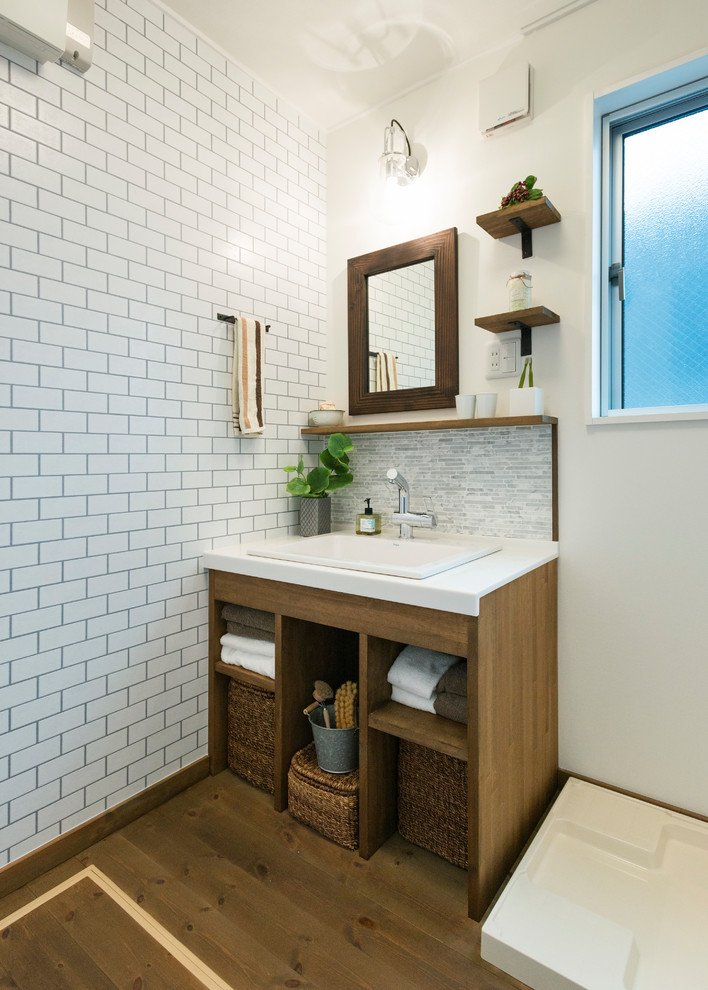 他の地域にあるインダストリアルスタイルのおしゃれな浴室 (オープンシェルフ、白いタイル、白い壁、無垢フローリング、茶色い床、白い洗面カウンター) の写真