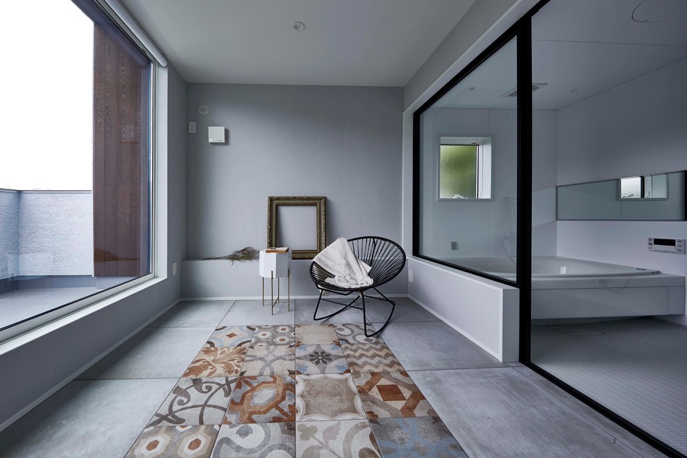 Immagine di una stanza da bagno design con vasca ad angolo, pareti grigie, pavimento in cemento e pavimento grigio
