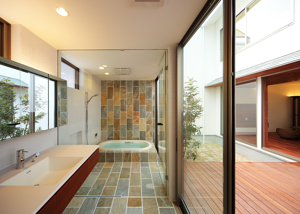 神戸にあるアジアンスタイルのおしゃれなマスターバスルーム (ドロップイン型浴槽、マルチカラーのタイル、白い壁、フラットパネル扉のキャビネット、濃色木目調キャビネット、シャワー付き浴槽	、石タイル、一体型シンク) の写真
