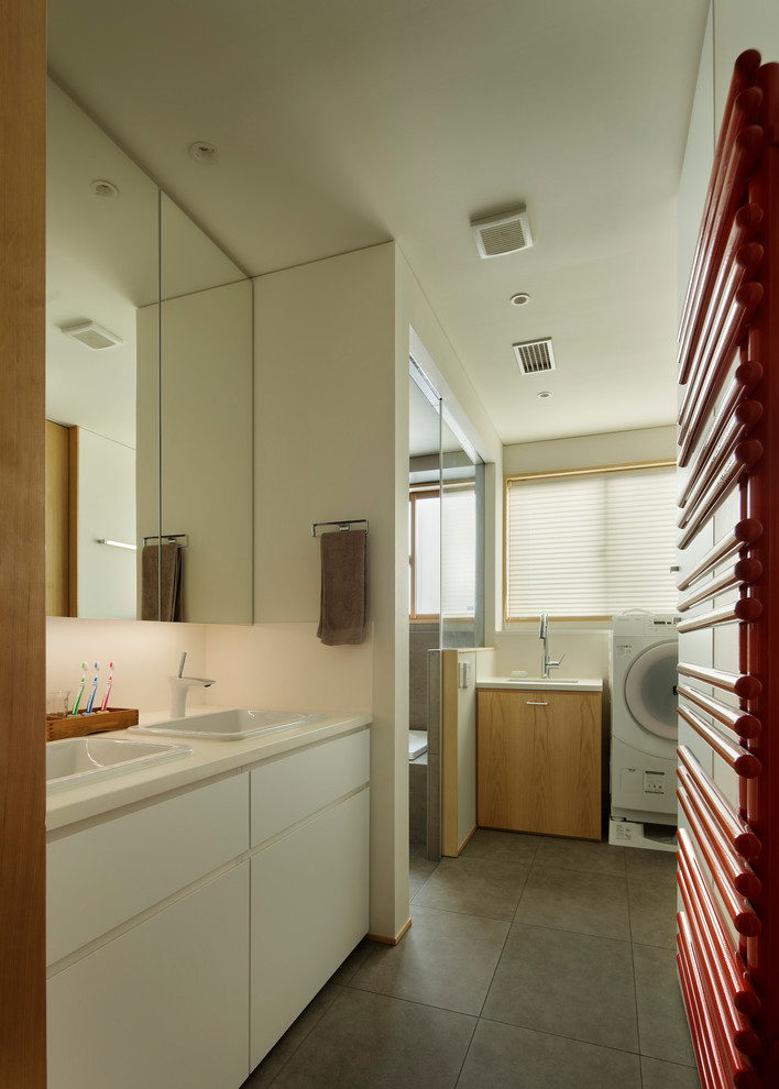 Mid-sized ceramic tile and gray floor walk-in shower photo in Tokyo with flat-panel cabinets, white cabinets, white walls, a drop-in sink, solid surface countertops, white countertops and a hinged shower door