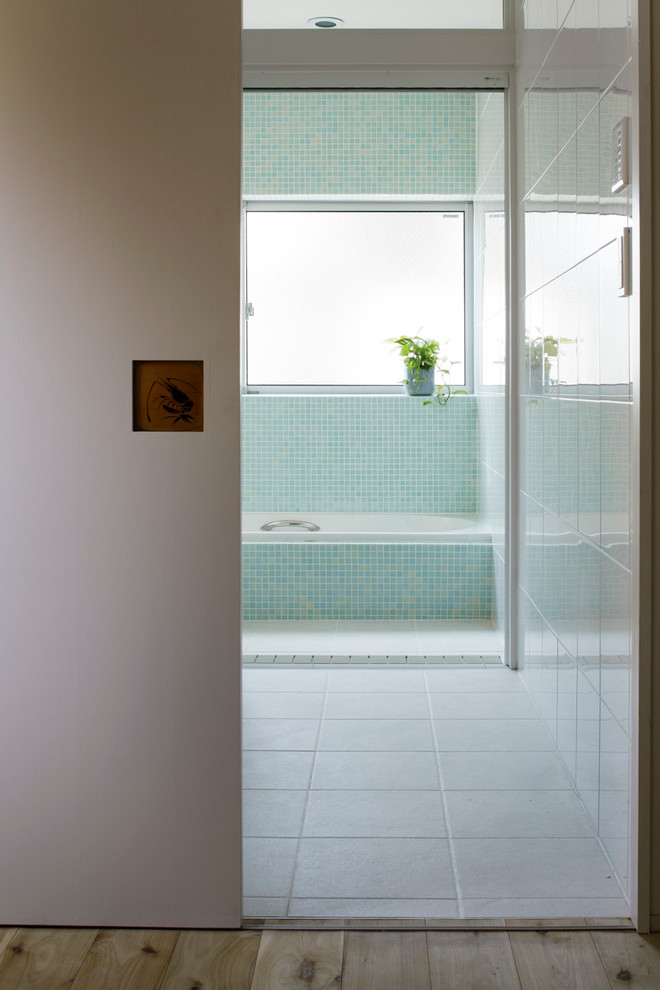 Immagine di una stanza da bagno padronale etnica di medie dimensioni con vasca da incasso, piastrelle bianche, piastrelle di vetro, pareti blu e pavimento con piastrelle in ceramica