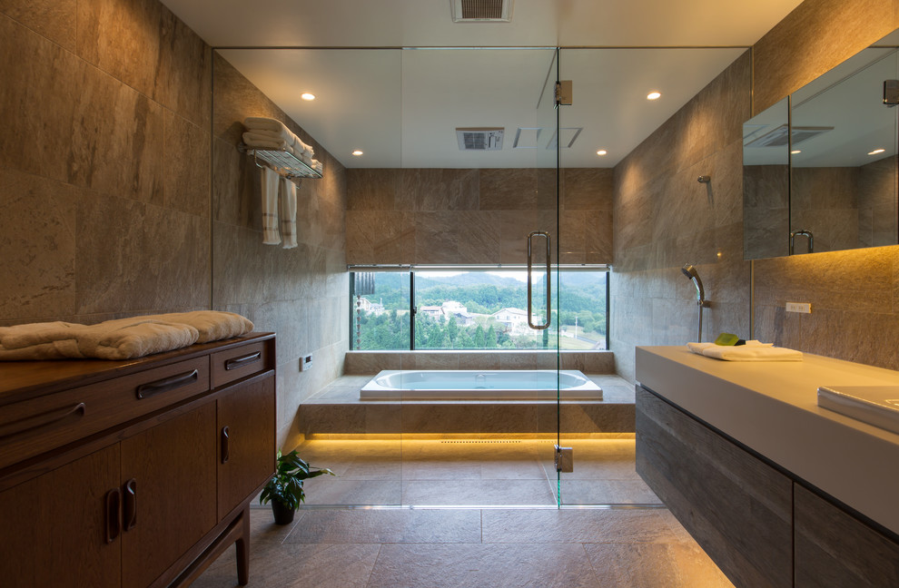 Idées déco pour une salle de bain principale contemporaine avec un placard à porte plane, des portes de placard grises, une baignoire posée, un carrelage beige, un mur beige et un lavabo posé.