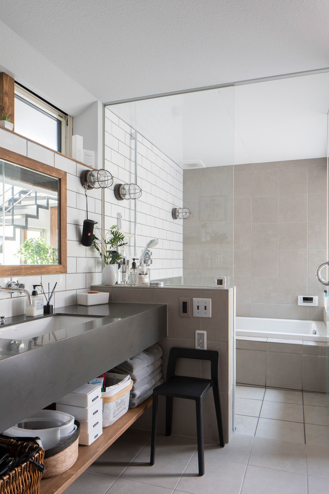 Immagine di una stanza da bagno design con vasca da incasso, piastrelle grigie, piastrelle bianche, pareti bianche, lavabo sottopiano, pavimento grigio e top grigio