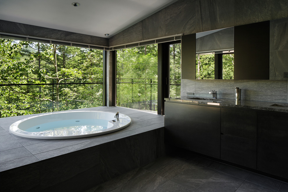 Foto di una stanza da bagno design con ante lisce, ante nere, vasca da incasso e lavabo sottopiano