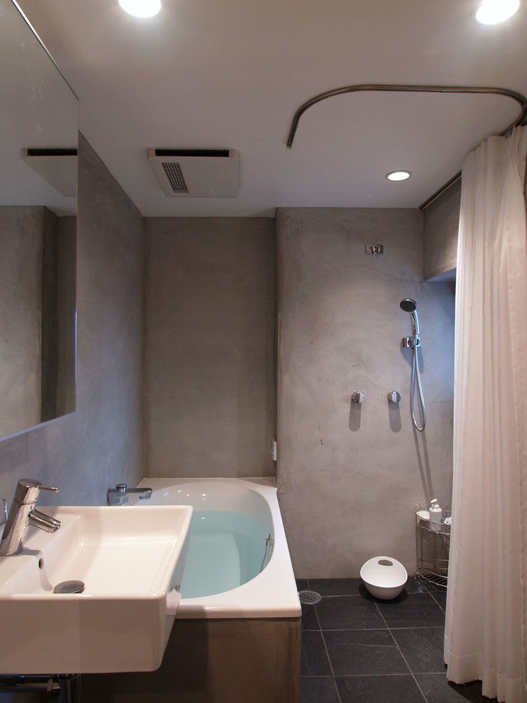 Imagen de cuarto de baño principal industrial de tamaño medio con bañera esquinera, ducha abierta, paredes grises, suelo de pizarra y lavabo suspendido