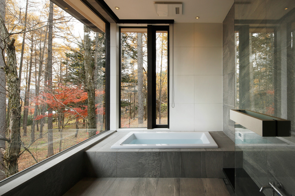 他の地域にあるコンテンポラリースタイルのおしゃれな浴室 (コーナー型浴槽、マルチカラーの壁、グレーの床) の写真