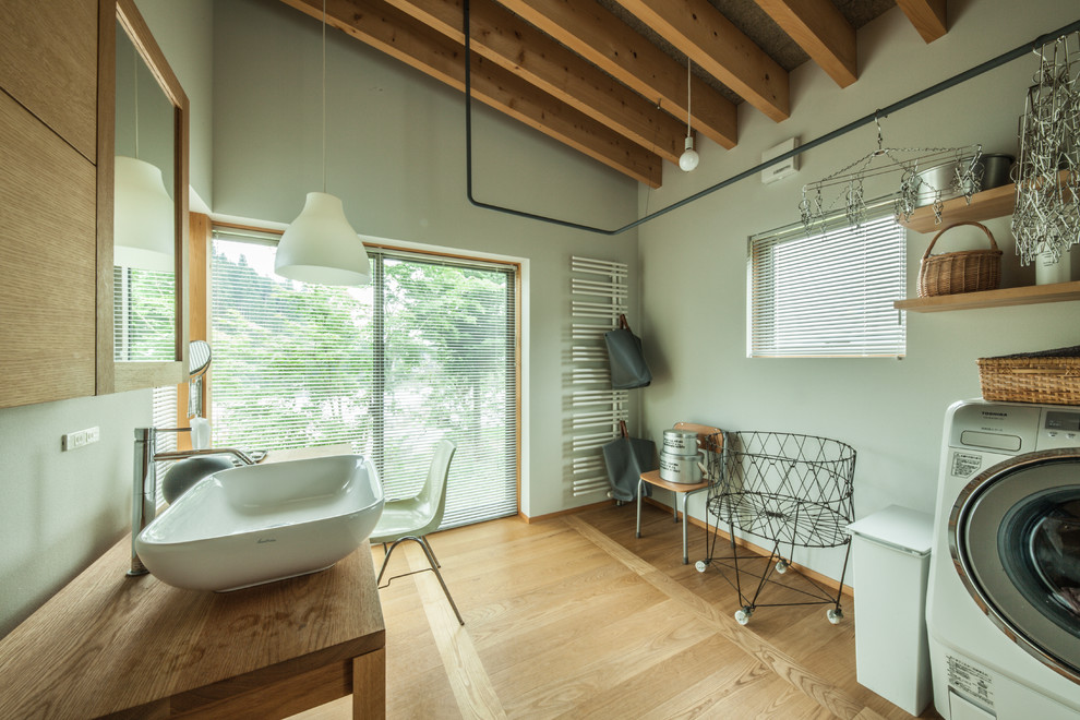 Modelo de cuarto de baño de estilo zen con paredes verdes, suelo de madera en tonos medios, lavabo sobreencimera, encimera de madera y suelo marrón