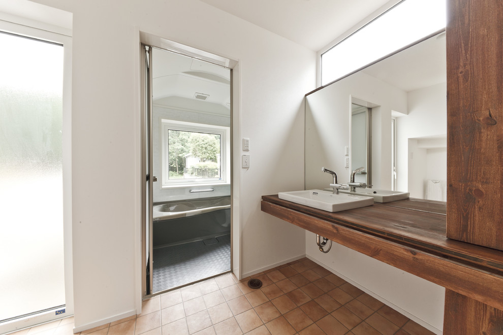 Свежая идея для дизайна: ванная комната в скандинавском стиле с белыми стенами, полом из терракотовой плитки, накладной раковиной, столешницей из дерева, коричневым полом и коричневой столешницей - отличное фото интерьера