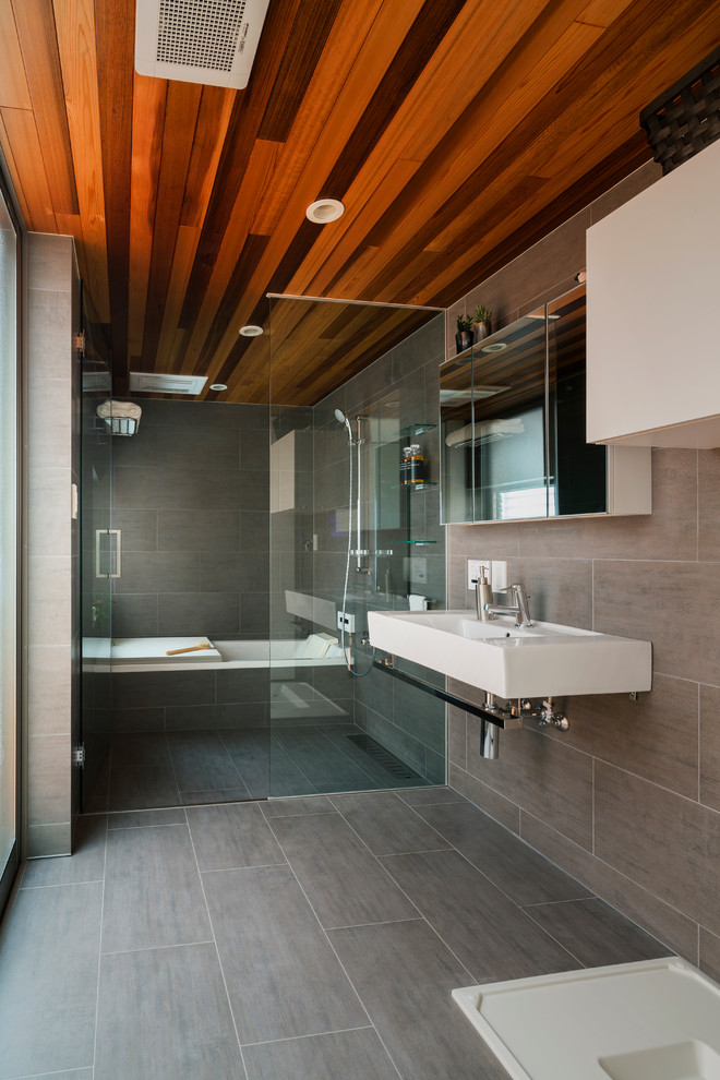 Ejemplo de cuarto de baño contemporáneo con armarios con paneles lisos, puertas de armario blancas, bañera encastrada, ducha abierta, baldosas y/o azulejos grises, paredes grises, lavabo suspendido y ducha abierta