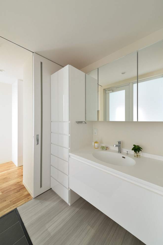 Стильный дизайн: ванная комната в стиле модернизм с белыми стенами, монолитной раковиной и серым полом - последний тренд