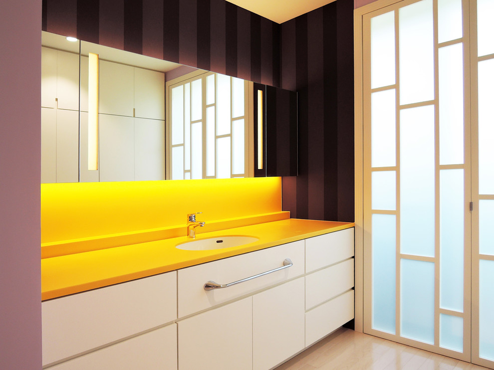 Imagen de cuarto de baño contemporáneo con armarios con paneles lisos, puertas de armario blancas, paredes púrpuras, lavabo integrado y suelo beige