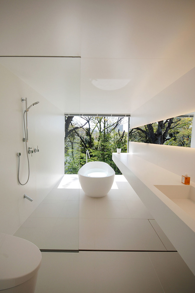 Immagine di una stanza da bagno minimalista con vasca freestanding, zona vasca/doccia separata, WC monopezzo, piastrelle bianche, pareti bianche, lavabo integrato, pavimento bianco e doccia aperta