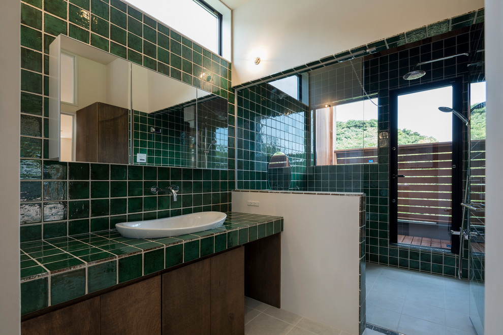 Photo of a world-inspired bathroom in Other with brown cabinets, green tiles, green walls, porcelain flooring, beige floors, a hinged door and a vessel sink.