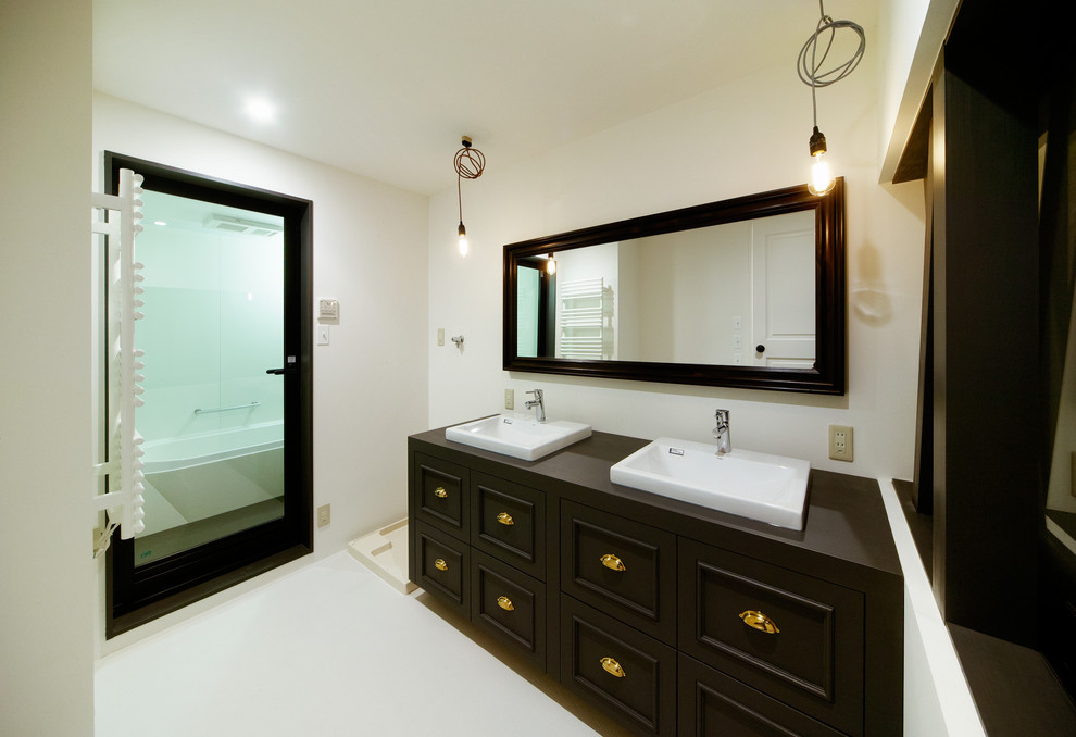 Idée de décoration pour une salle de bain design avec un placard à porte plane, des portes de placard noires, un mur blanc, un plan de toilette en bois et un lavabo posé.