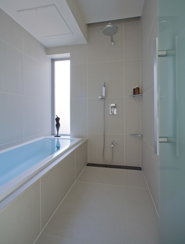 На фото: ванная комната в современном стиле с ванной в нише, двойным душем, бежевой плиткой и бежевыми стенами