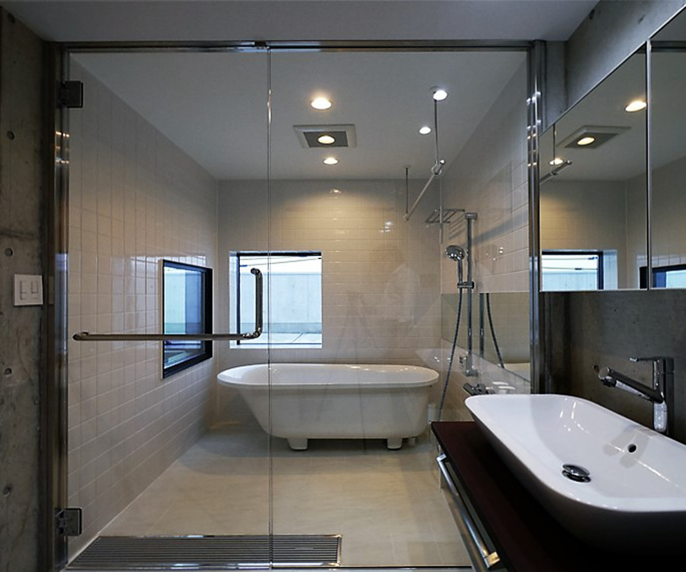 横浜にあるモダンスタイルのおしゃれな浴室 (置き型浴槽、バリアフリー、白いタイル、グレーの壁、ベッセル式洗面器、茶色いキャビネット、白い洗面カウンター、洗面台1つ) の写真