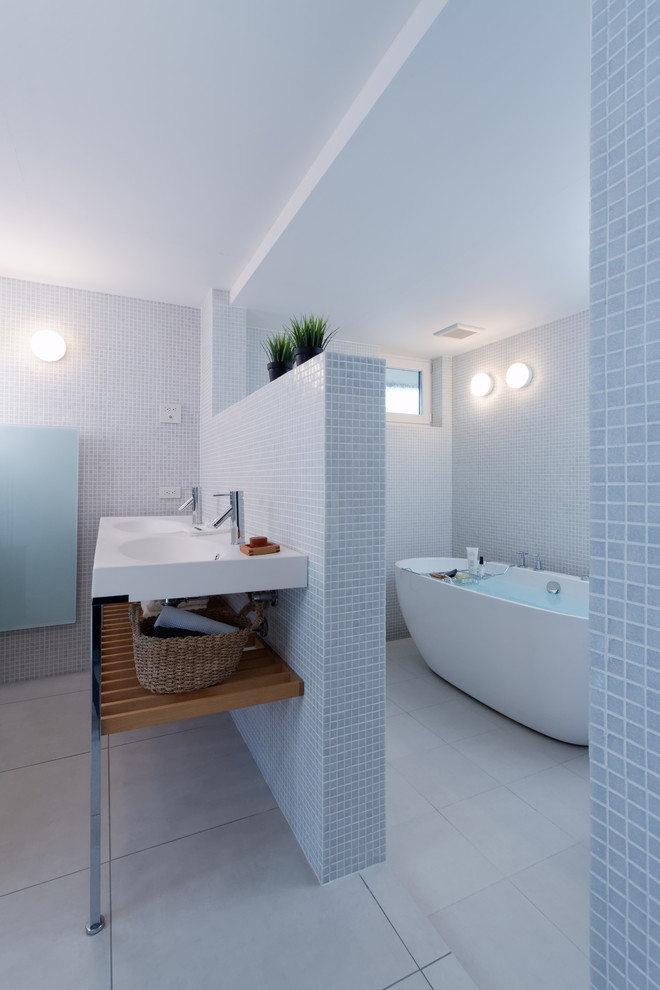 Design ideas for a scandinavian bathroom in Other with open cabinets, a freestanding bath, blue tiles, white walls and grey floors.