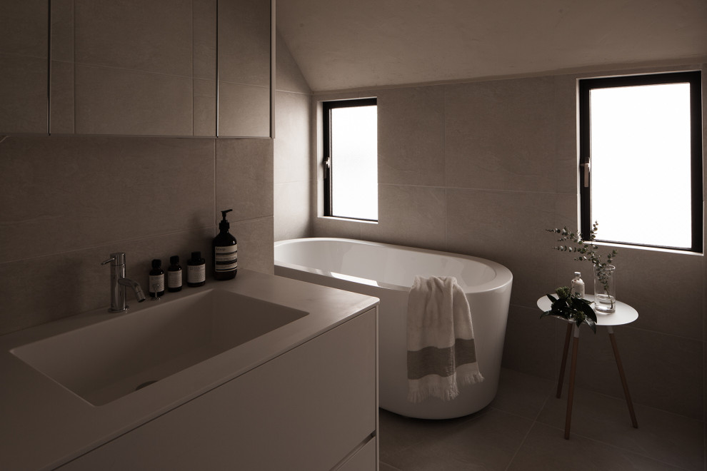東京23区にあるおしゃれな浴室 (置き型浴槽、グレーのタイル、セラミックタイル、人工大理石カウンター、白い洗面カウンター、洗面台1つ、造り付け洗面台) の写真