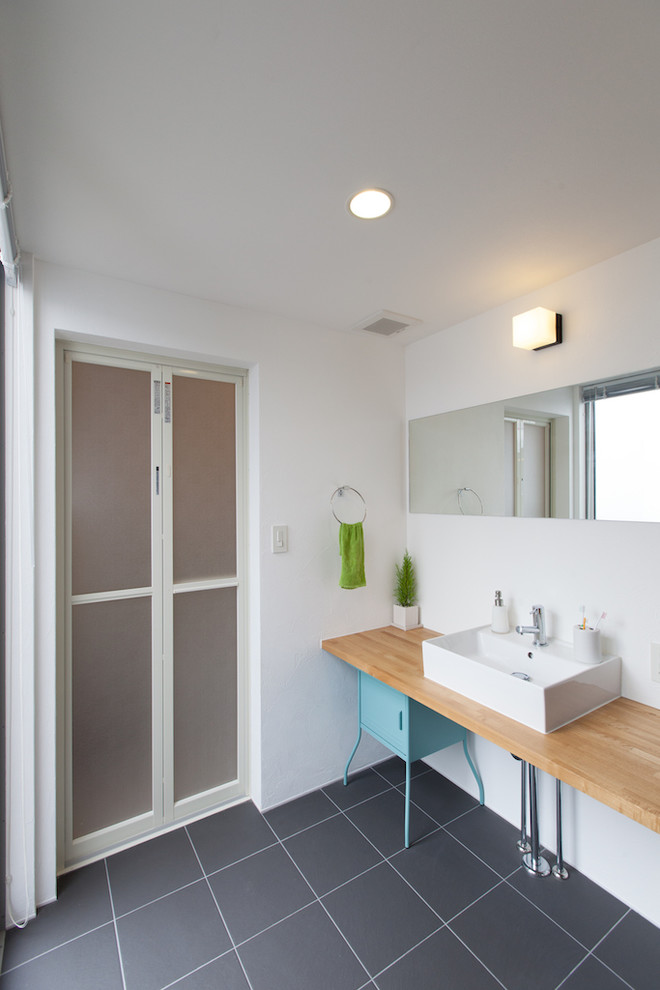他の地域にある北欧スタイルのおしゃれな浴室 (ベッセル式洗面器、青いキャビネット、木製洗面台、白い壁、セラミックタイルの床、ブラウンの洗面カウンター、落し込みパネル扉のキャビネット) の写真