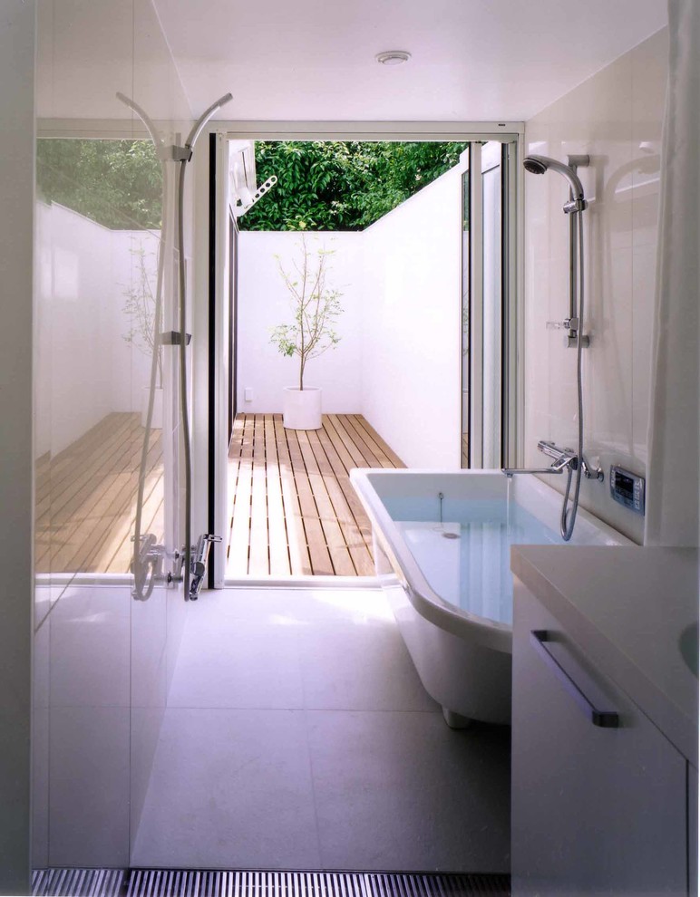 Cette image montre une salle de bain minimaliste avec un placard à porte plane, des portes de placard blanches, une baignoire indépendante, une douche double et un mur blanc.