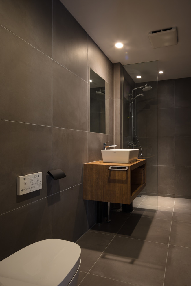 Стильный дизайн: ванная комната в стиле модернизм с черной плиткой, черными стенами, столешницей из дерева, черным полом, открытым душем и коричневой столешницей - последний тренд