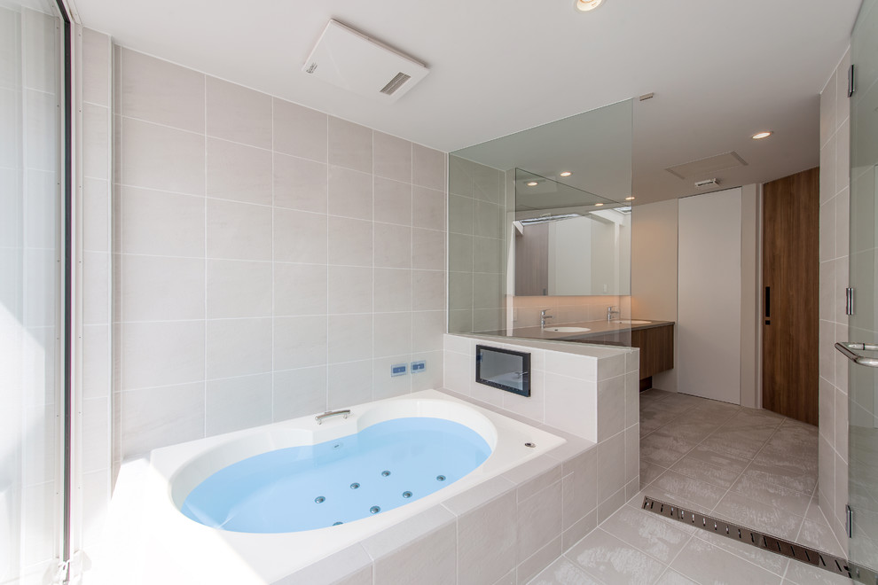 横浜にあるモダンスタイルのおしゃれな浴室 (コーナー型浴槽、ベージュの壁、ベージュの床) の写真