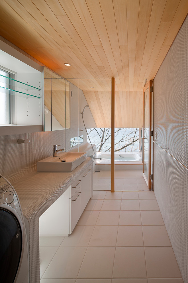 Modelo de cuarto de baño minimalista con armarios con paneles lisos, puertas de armario blancas, bañera encastrada, baldosas y/o azulejos blancos, paredes blancas y lavabo sobreencimera