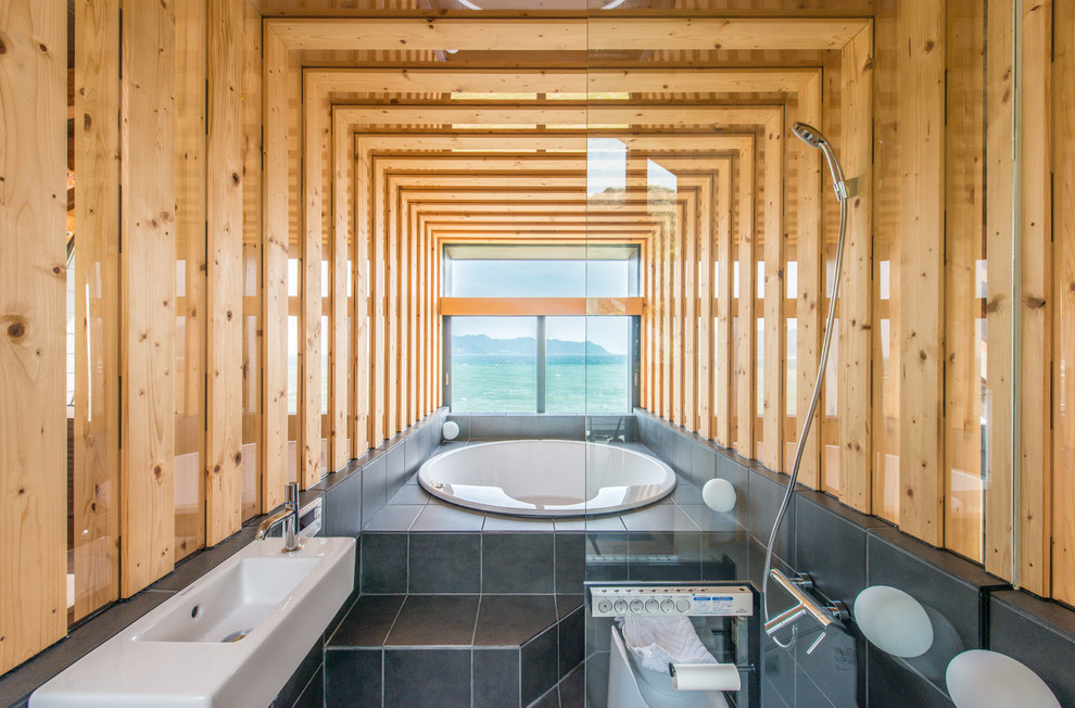 Réalisation d'une salle de bain principale design avec une baignoire posée, un carrelage gris, une douche ouverte, des carreaux de céramique, un mur marron, un sol en carrelage de céramique et aucune cabine.