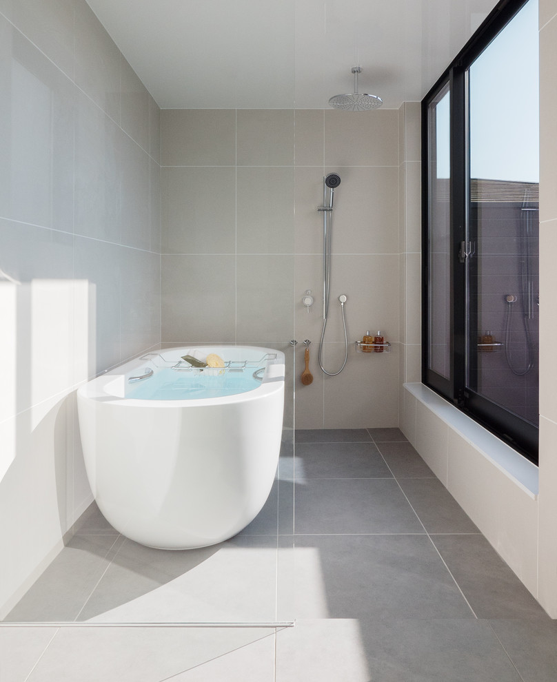 Foto på ett funkis badrum, med ett fristående badkar, en öppen dusch, grå väggar, grått golv och med dusch som är öppen