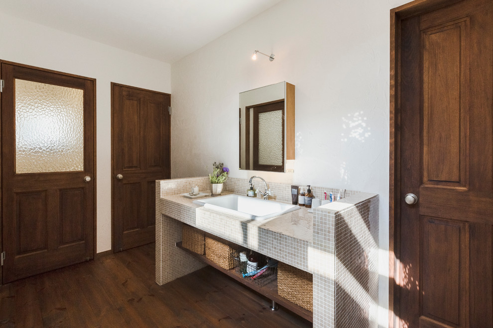 На фото: ванная комната в восточном стиле с открытыми фасадами, бежевой плиткой, столешницей из плитки, белыми стенами, темным паркетным полом, накладной раковиной и коричневым полом с