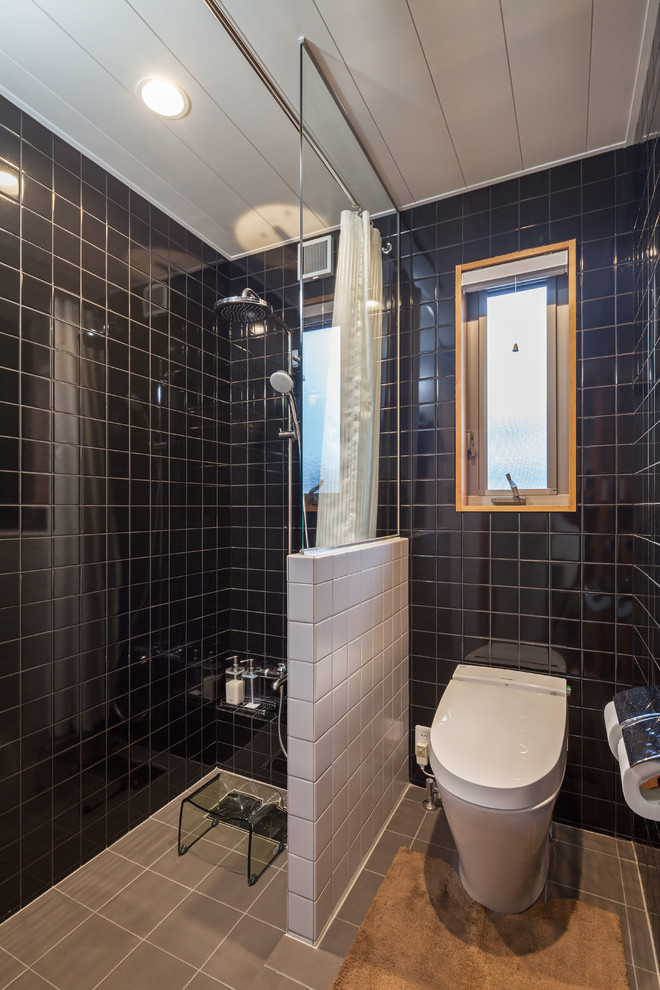 Diseño de cuarto de baño de estilo zen con paredes azules, suelo de azulejos de cemento, suelo gris, ducha abierta, sanitario de una pieza, baldosas y/o azulejos negros y ducha con cortina