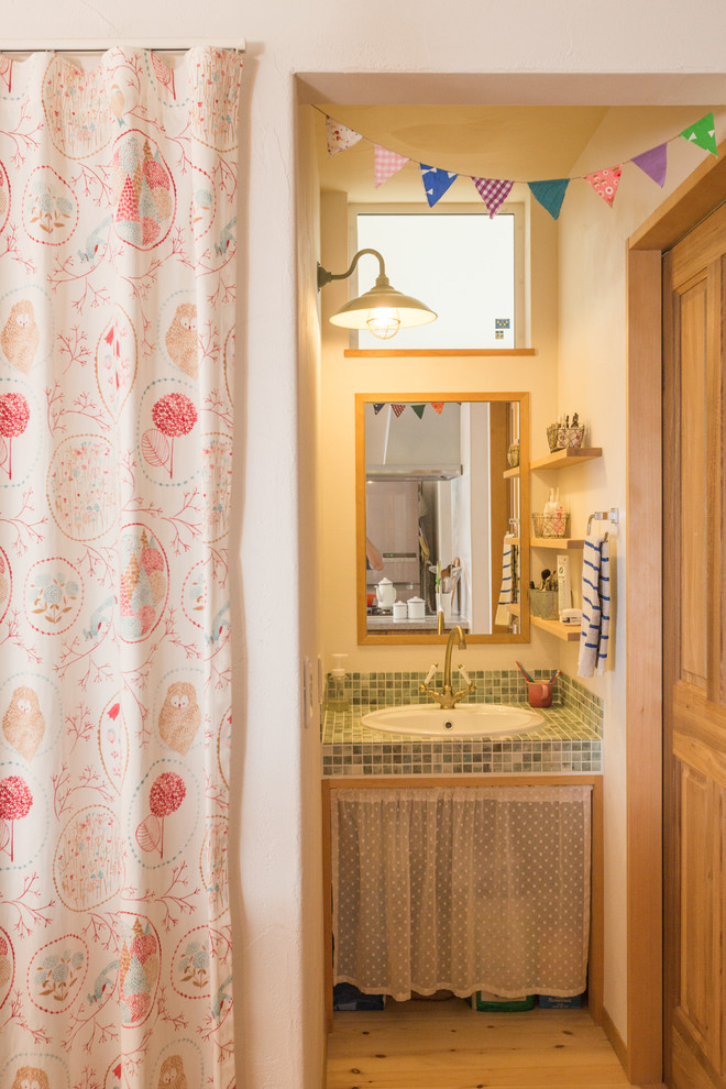 Modelo de cuarto de baño de estilo zen pequeño con paredes blancas, suelo de madera clara, armarios abiertos, lavabo encastrado, encimera de azulejos y suelo marrón
