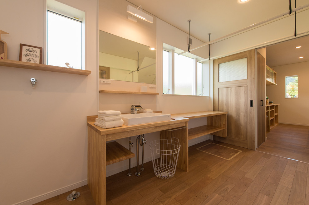 Idéer för ett modernt badrum, med vita väggar, mellanmörkt trägolv, ett fristående handfat och träbänkskiva