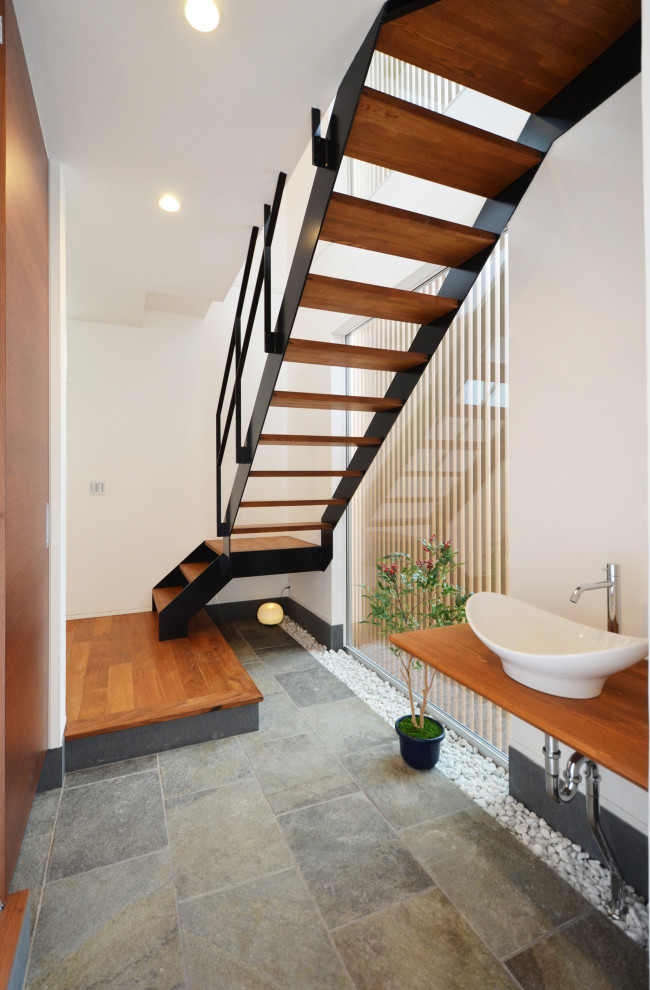 Imagen de cuarto de baño de estilo zen grande con puertas de armario de madera oscura, paredes blancas, lavabo sobreencimera, encimera de madera, suelo gris y encimeras marrones