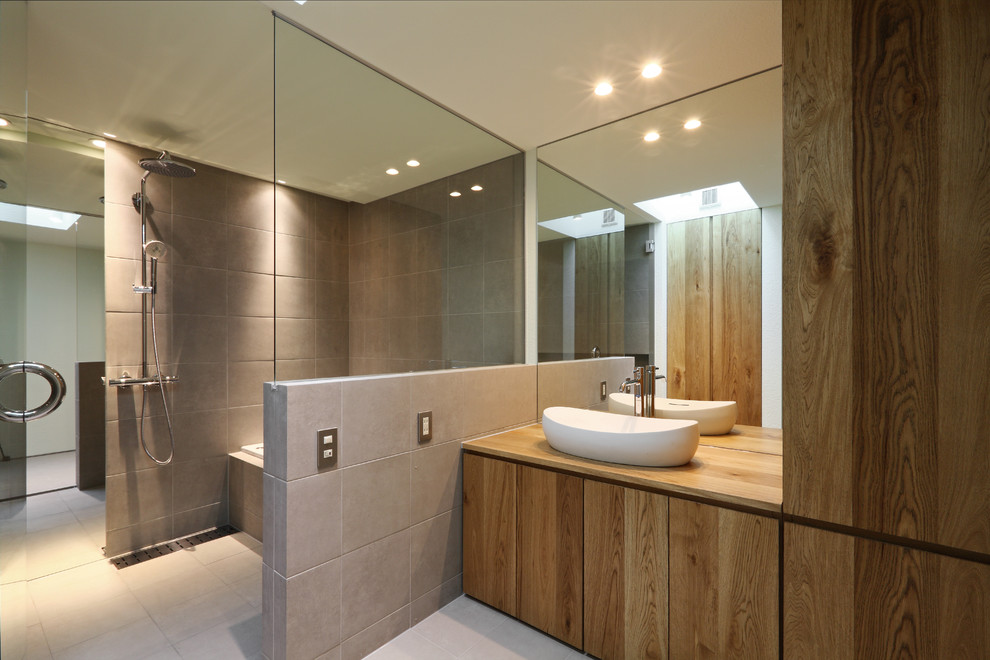 Inspiration för moderna en-suite badrum, med släta luckor, skåp i mellenmörkt trä, en kantlös dusch, grå kakel, ett fristående handfat och grå väggar