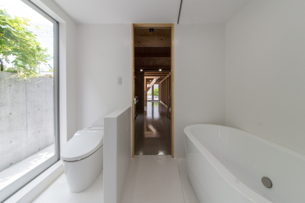 Bild på ett industriellt badrum, med ett fristående badkar, vita väggar och vitt golv