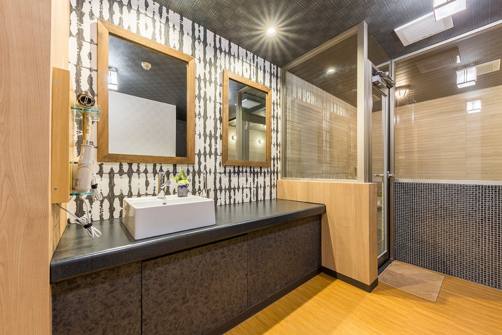 Diseño de cuarto de baño de estilo zen con armarios con paneles lisos, puertas de armario negras, paredes multicolor, suelo de madera en tonos medios, lavabo sobreencimera y suelo marrón