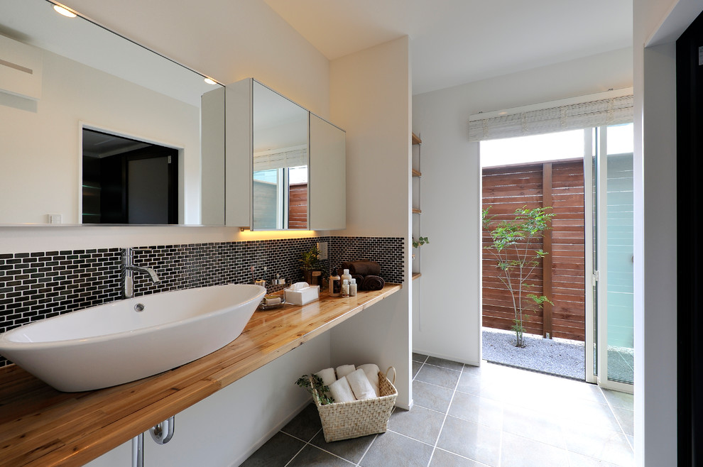 他の地域にあるアジアンスタイルのおしゃれな浴室 (ベッセル式洗面器、グレーの床、ブラウンの洗面カウンター) の写真