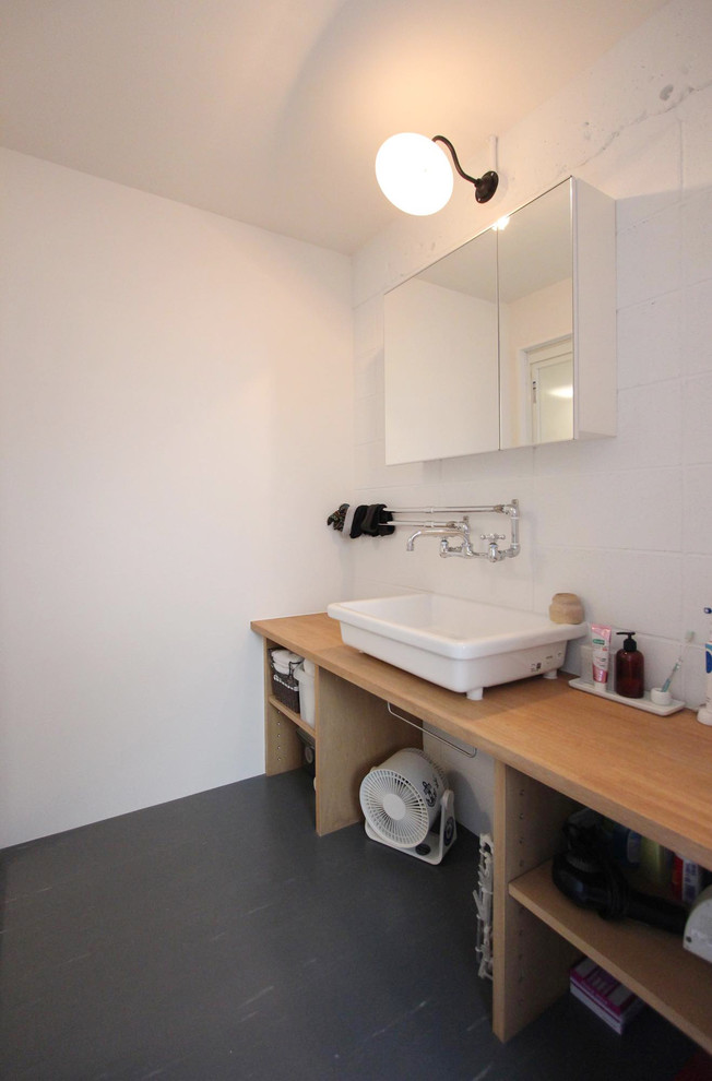 東京23区にある北欧スタイルのおしゃれな浴室 (オープンシェルフ、白い壁、ベッセル式洗面器、木製洗面台、黒い床) の写真