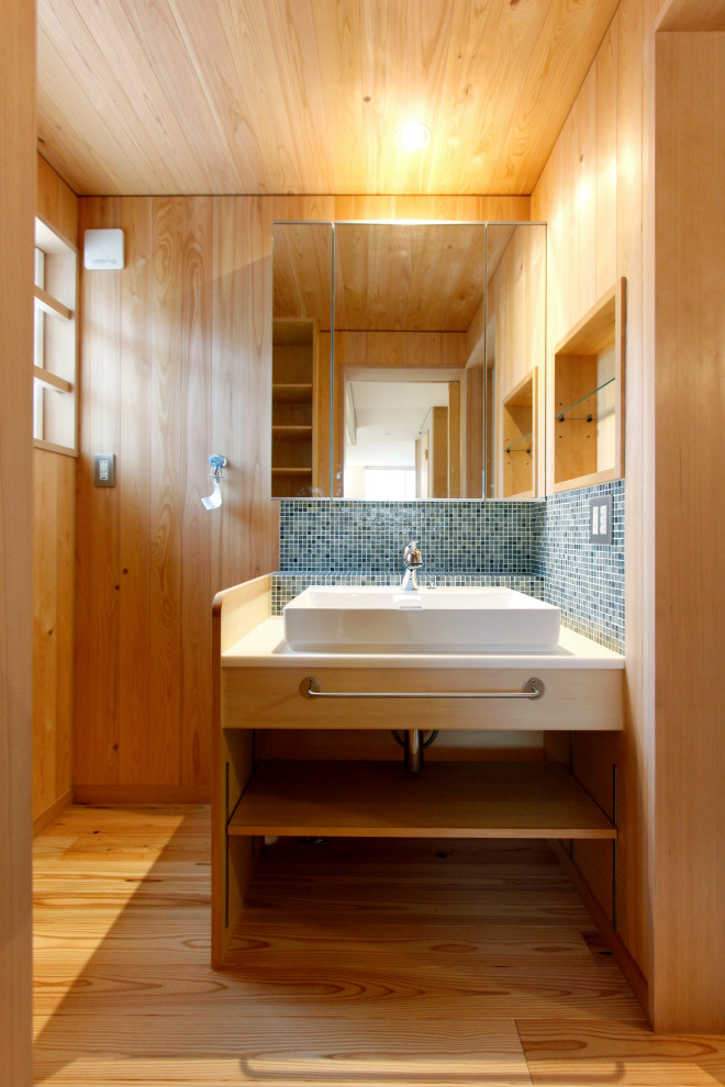 Bild på ett mellanstort orientaliskt vit vitt badrum med dusch, med öppna hyllor, skåp i ljust trä, blå kakel, beige väggar, mellanmörkt trägolv, ett fristående handfat och beiget golv