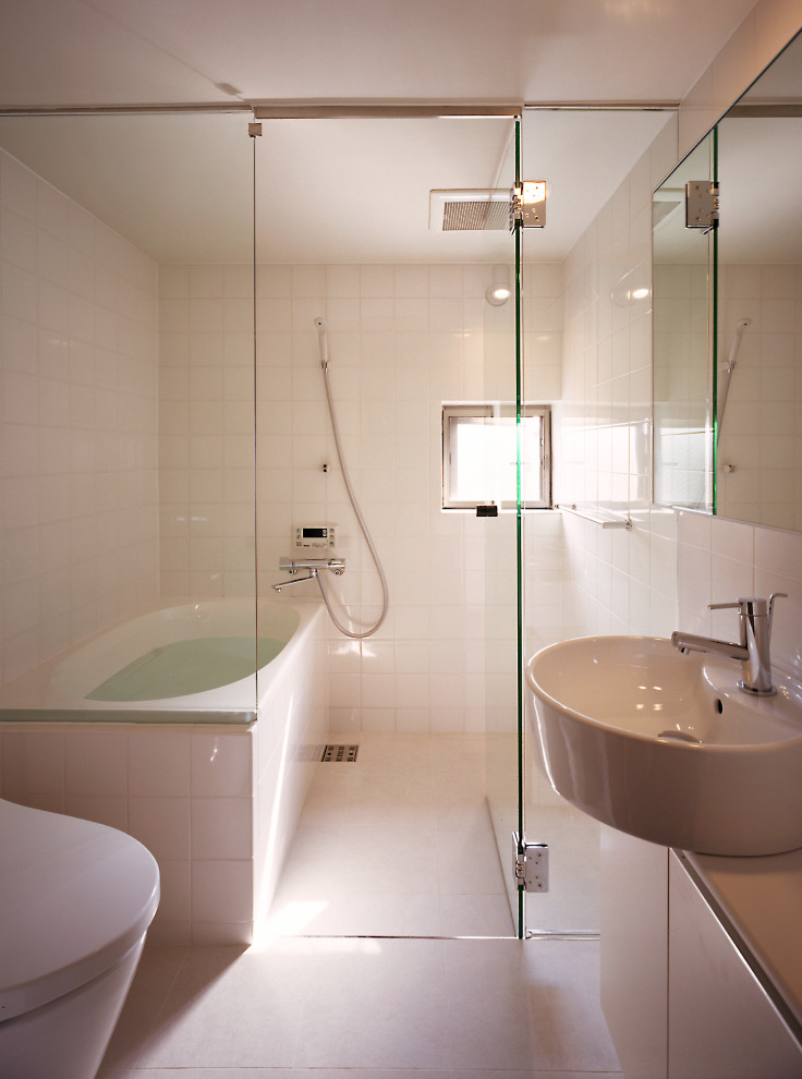 Стильный дизайн: главная ванная комната среднего размера в стиле модернизм с фасадами с декоративным кантом, белыми фасадами, накладной ванной, душем над ванной, унитазом-моноблоком, белой плиткой, керамической плиткой, белыми стенами, полом из керамической плитки, настольной раковиной, столешницей из искусственного камня, белым полом, душем с распашными дверями, белой столешницей и окном - последний тренд