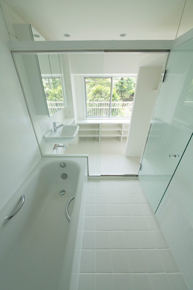 Imagen de cuarto de baño principal minimalista de tamaño medio con armarios abiertos, bañera encastrada sin remate, baldosas y/o azulejos blancos, paredes blancas y lavabo suspendido
