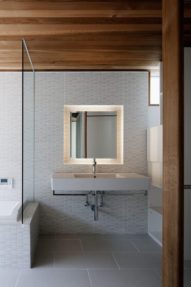 Cette photo montre une salle de bain moderne avec un carrelage gris, un mur gris, un sol gris, des carreaux de porcelaine, un sol en carrelage de porcelaine et un lavabo suspendu.