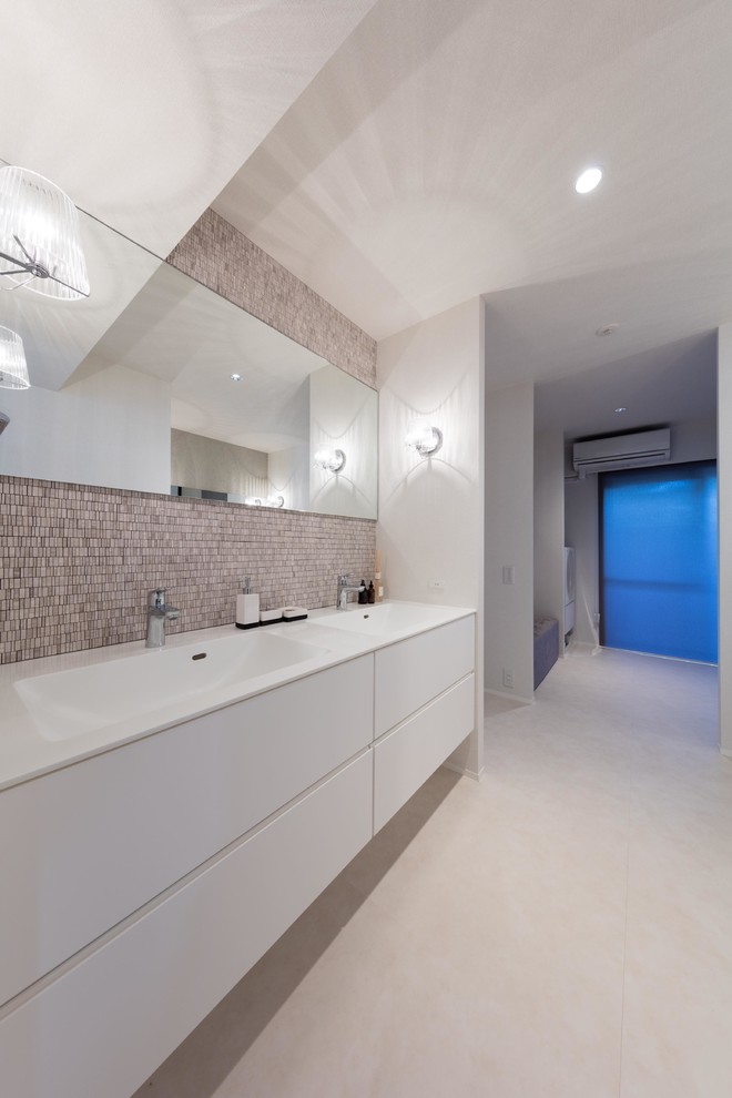 Cette image montre une salle de bain design avec un placard à porte plane, des portes de placard blanches, un carrelage gris, un carrelage rose, un carrelage blanc, un mur blanc, un lavabo intégré, un sol beige, un plan de toilette en bois et un plan de toilette marron.